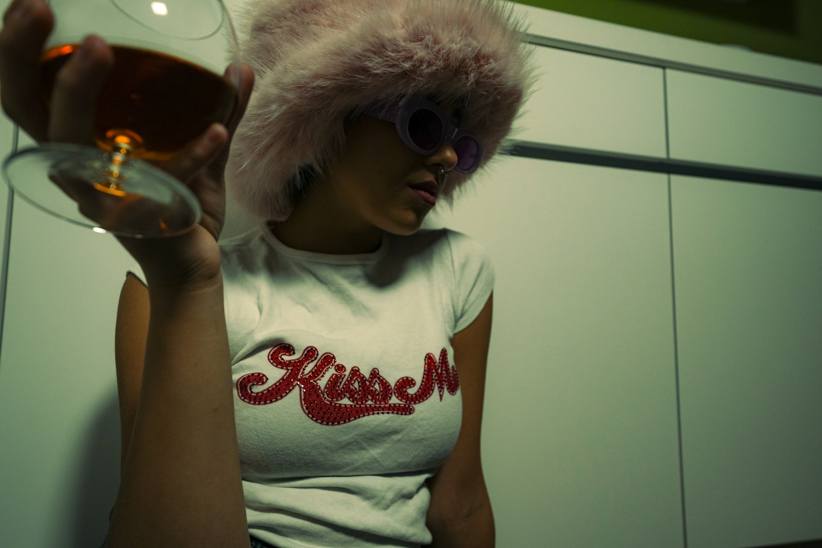a woman wearing a white shirt and a fur hat holding a glass of wine