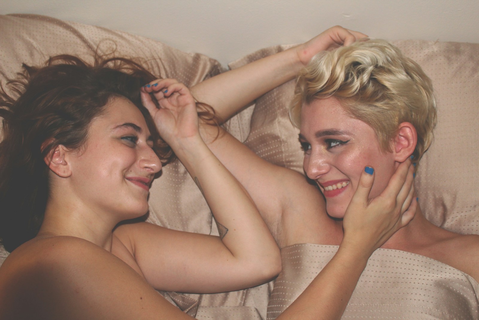two women laying on bed